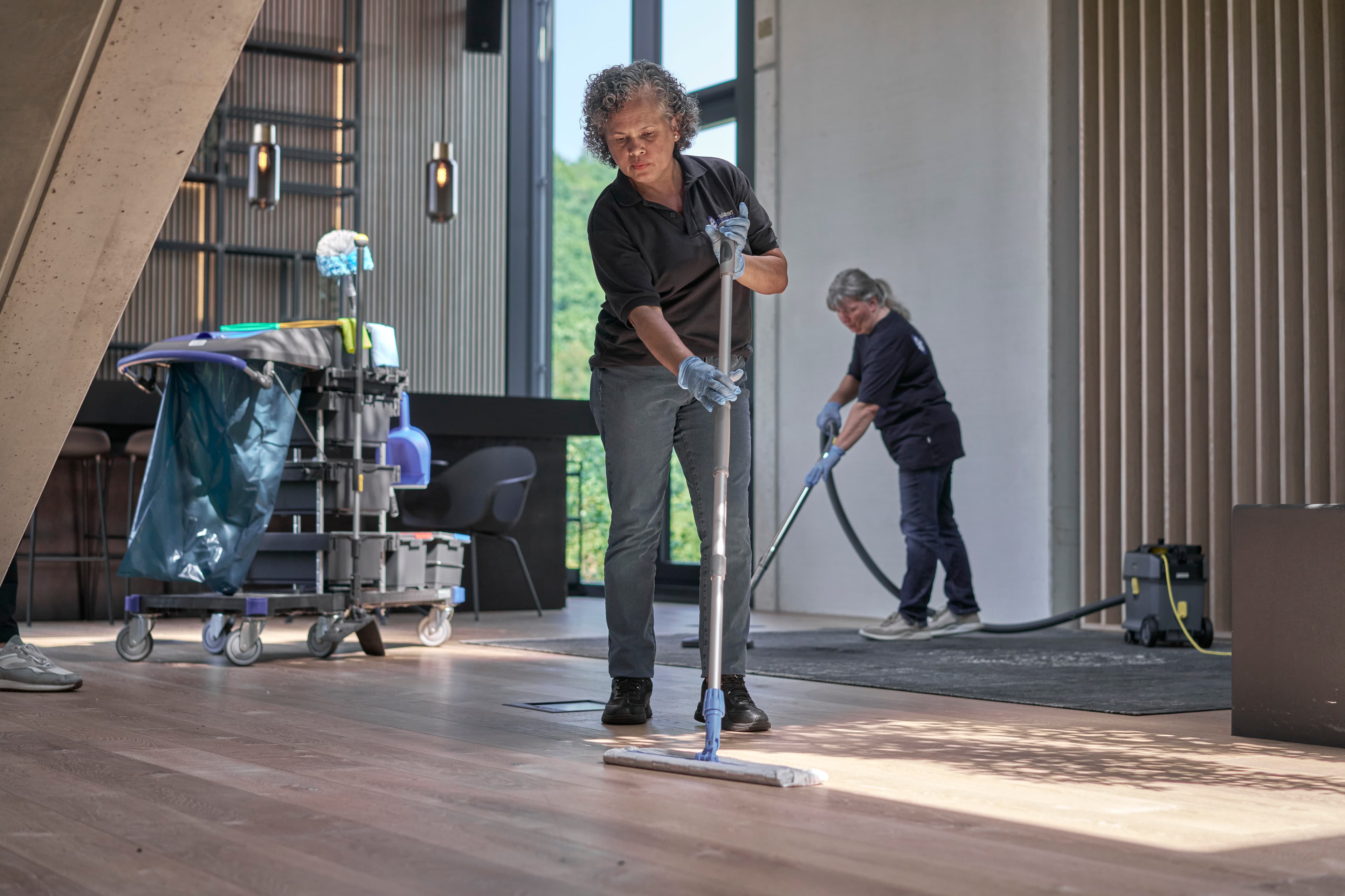 Mitarbeiter reinigen einen modernen Büroraum mit professioneller Ausrüstung.